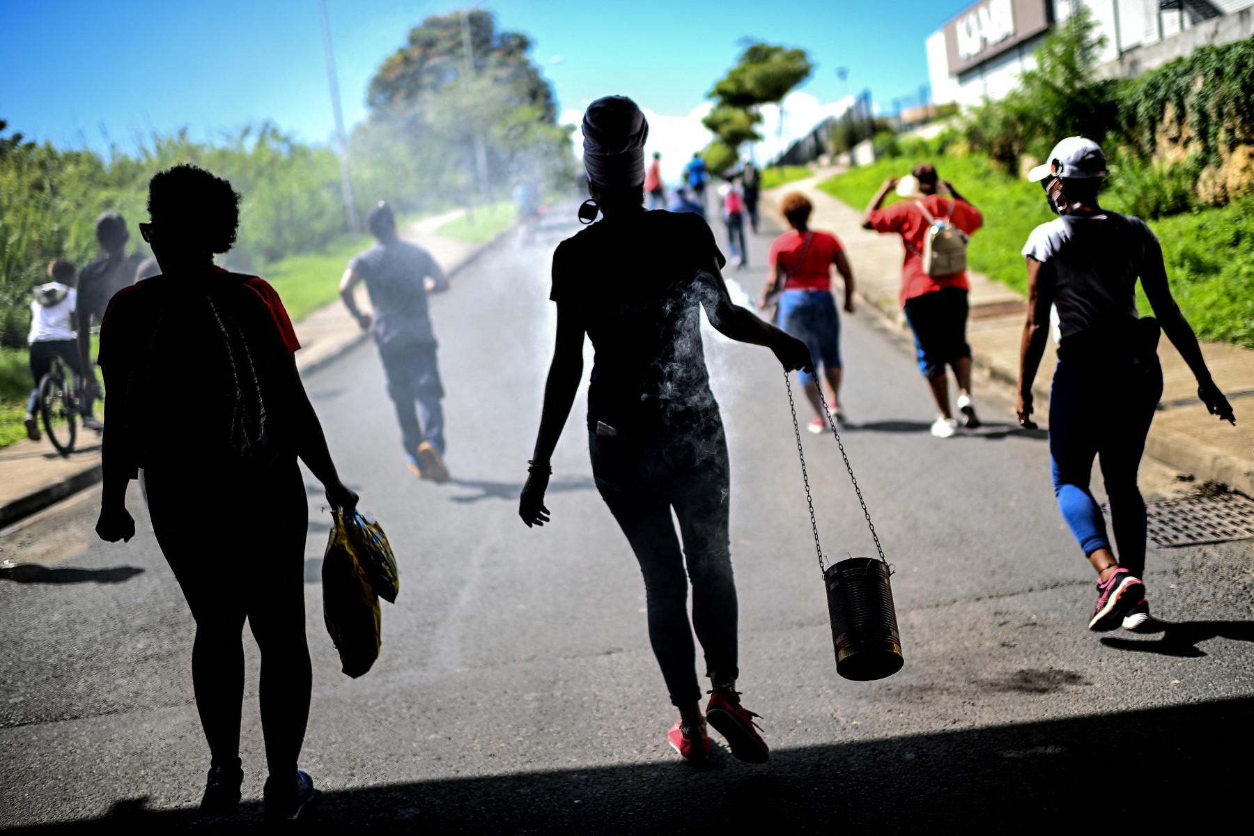 Une manifestante porte une boîte contenant de l'encens enflammé lors d'une marche de protestation contre les mesures visant à limiter la propagation du Covid-19 aux Abymes, à l'extérieur de Pointe-a-Pitre, sur l'île française de la Guadeloupe, dans les Caraïbes, le 24 novembre 2021. (Photo Christophe Archambault AFP)