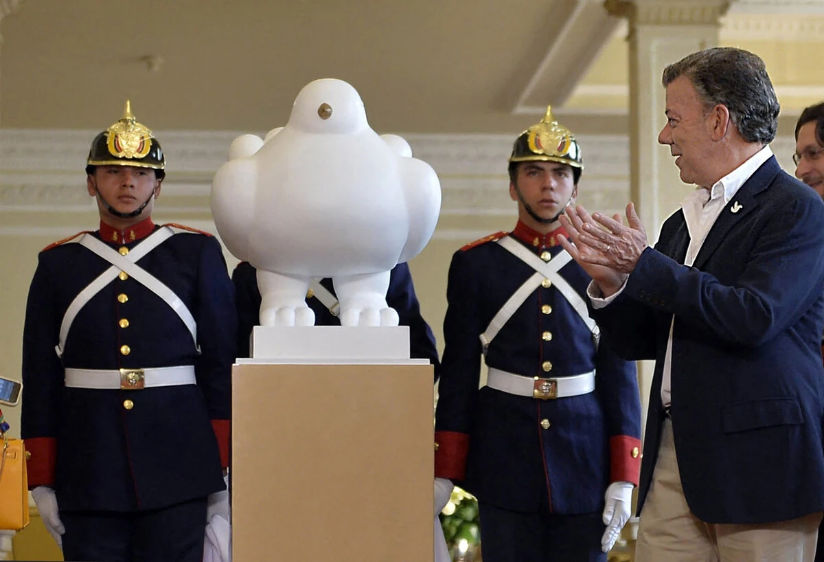 Photo diffusée par la présidence colombienne montrant le président colombien Juan Manuel Santos (à droite) applaudissant après avoir reçu la sculpture "La colombe de la paix", un cadeau de l'artiste colombien Fernando Botero, au palais présidentiel de Narino à Bogota, le 24 septembre 2016. (Photo Juan David Tena / Présidence colombienne / AFP)
