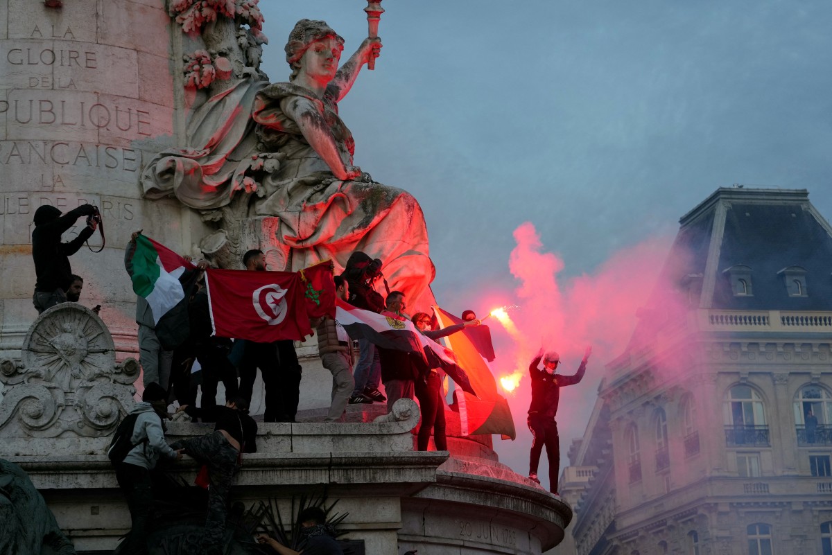 Des manifestants allument des fusées éclairantes alors qu'ils grimpent sur le Monument à la République lors d'une manifestation non autorisée de soutien aux Palestiniens à Paris, le 12 octobre 2023. (Photo Dimitar Dilkoff AFP)