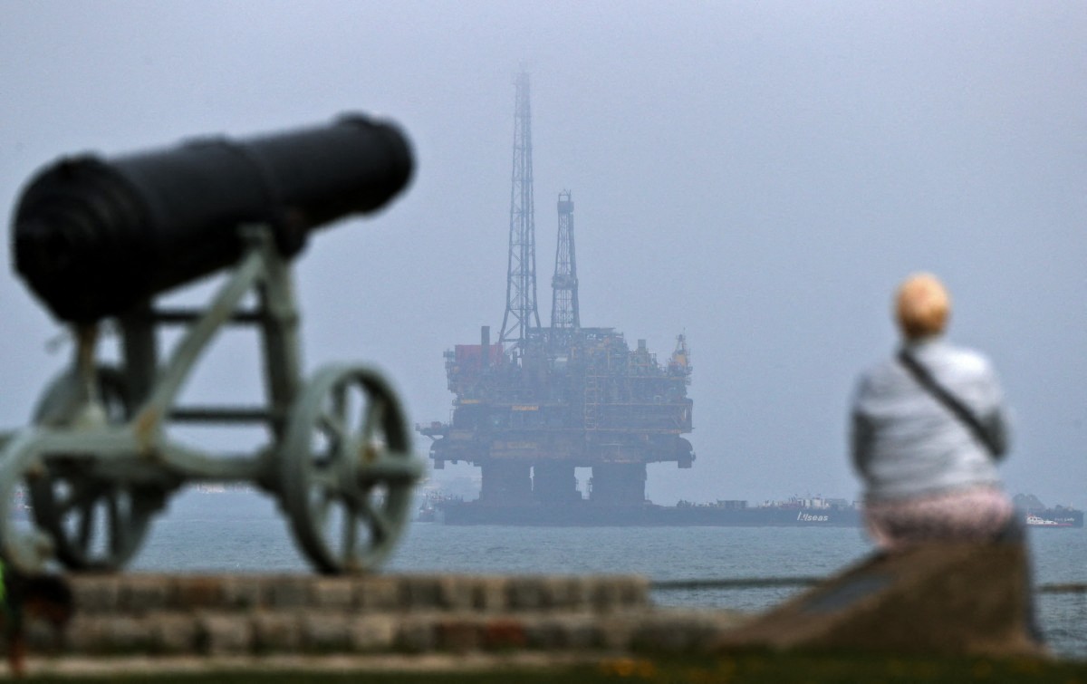 Un passant regarde la mer devant la plateforme de forage pétrolier offshore Brent Delta Topside de Shell remorquée au large de Hartlepool, dans le nord-est de l'Angleterre, le 2 mai 2017, en route vers le port d'Able Seaton pour démantèlement. (Photo Scott Heppell AFP)
