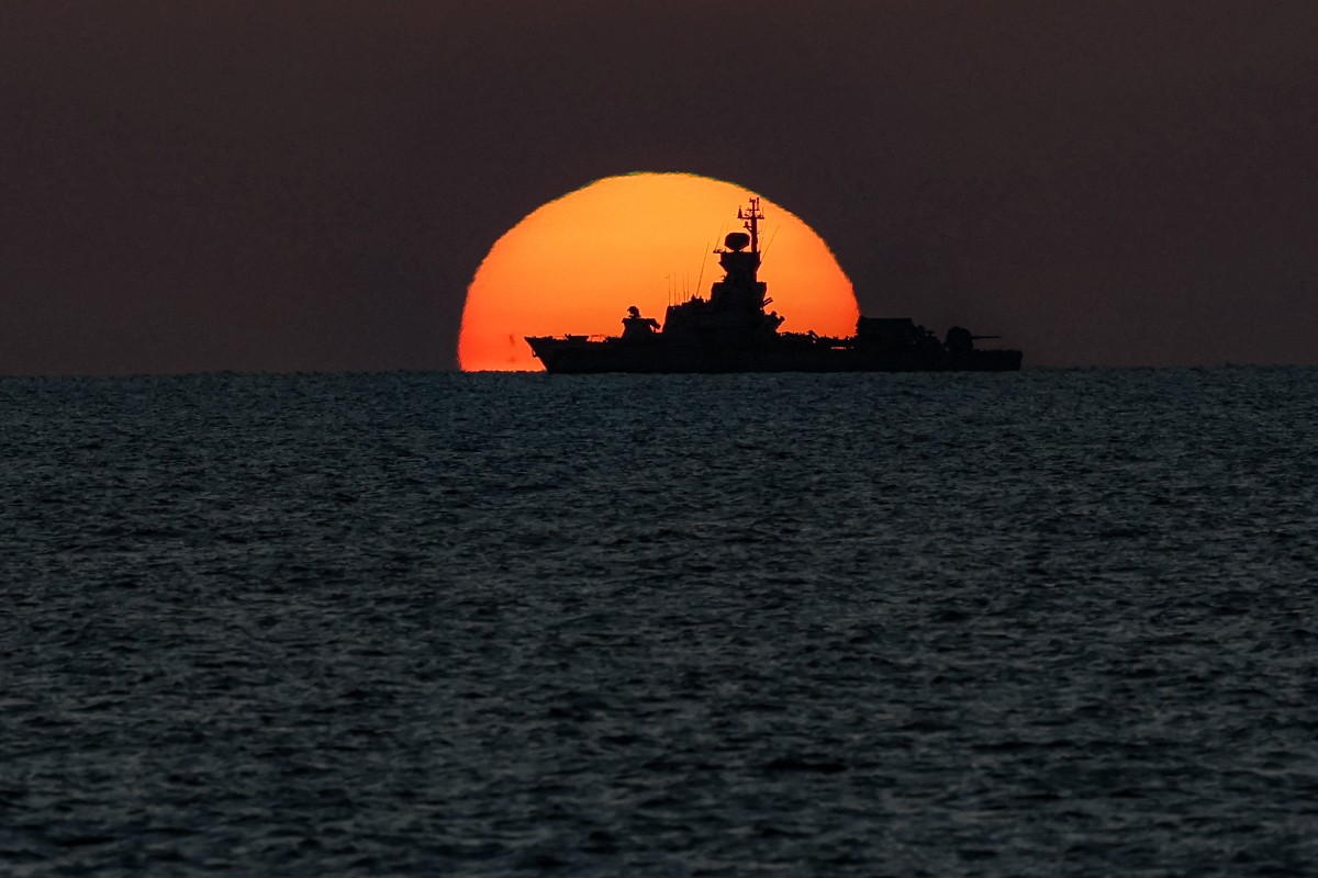 Le soleil se couche derrière un navire de guerre naviguant dans les eaux de la Méditerranée au large de la ville d'Acre (également connue sous le nom d'Akko), au nord d'Israël, le 3 novembre 2023. (Photo Ahmad Gharabli AFP)