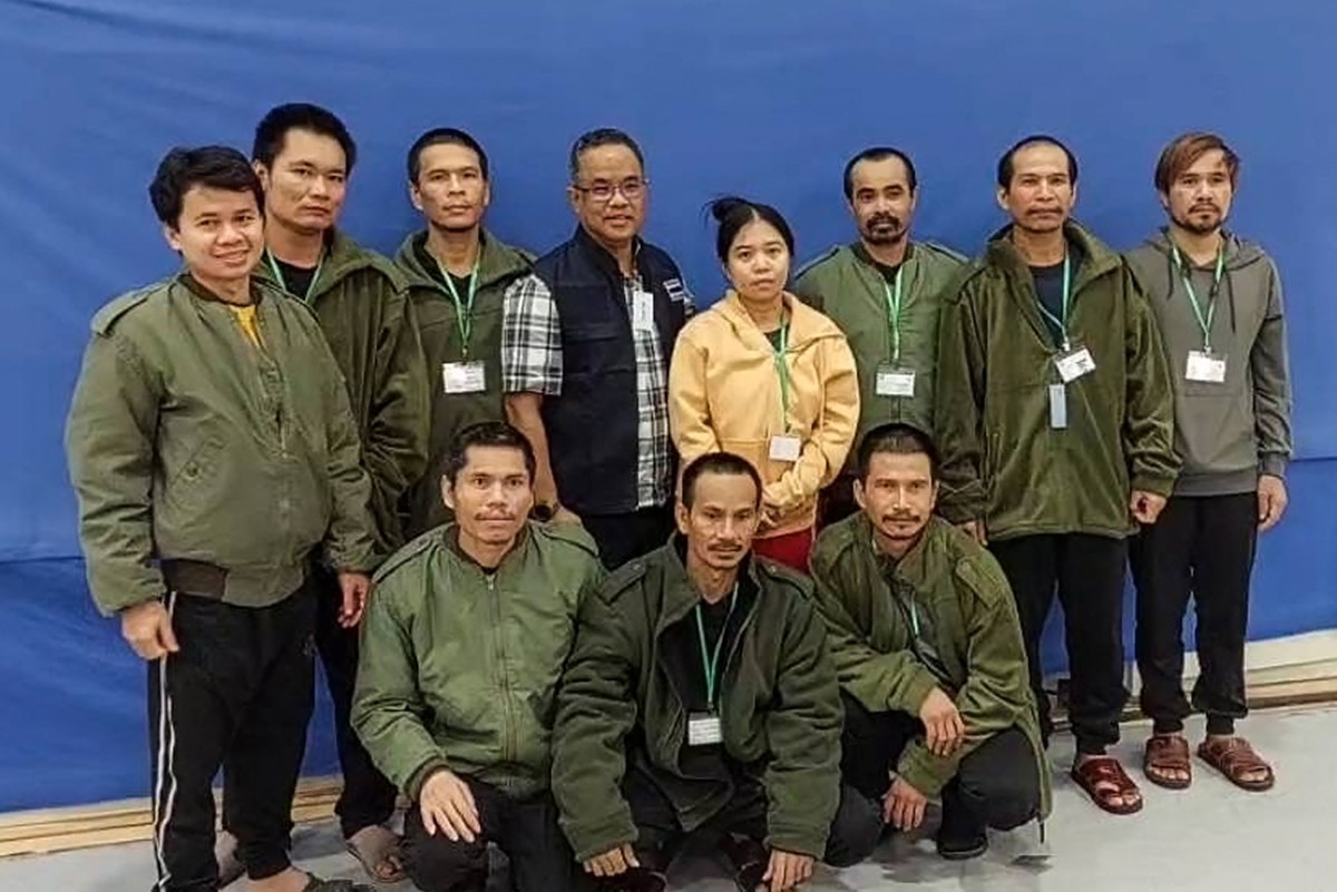 Cette photo non datée et non localisée publiée le 25 novembre 2023 par le ministère thaïlandais des Affaires étrangères montre un officiel thaïlandais (au centre) posant pour une photo de groupe avec 10 otages thaïlandais libérés en Israël, après qu'ils aient été libérés par le Hamas. (Photo distribuée par le ministère thaïlandais des Affaires étrangères AFP)