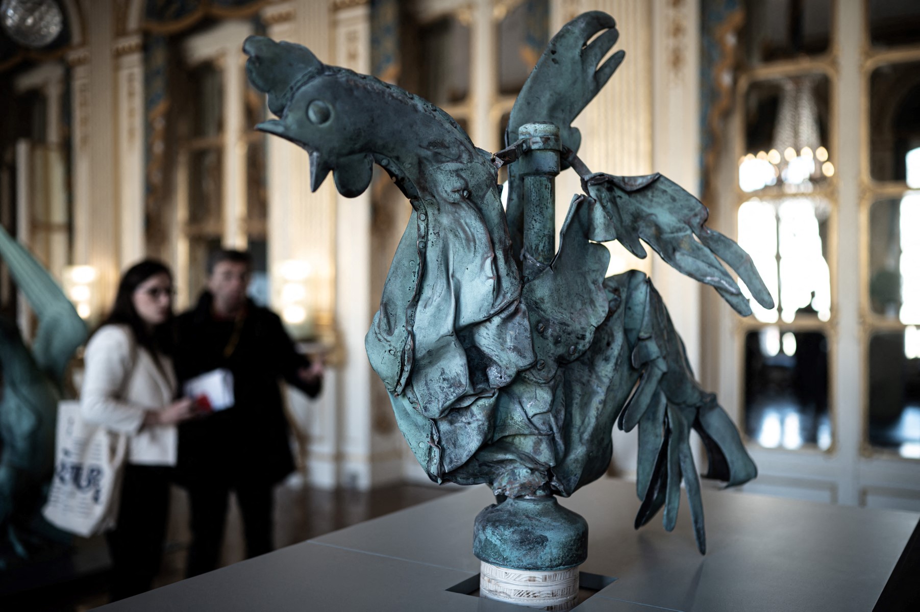 Des personnes regardent le coq qui trônait au sommet de la flèche de la cathédrale Notre-Dame, lors d'une présentation de l'exposition "Revoir Notre-Dame de Paris" au ministère de la Culture à Paris, le 20 septembre 2019 dans le cadre des journées du patrimoine. (Photo Philippe Lopez AFP)