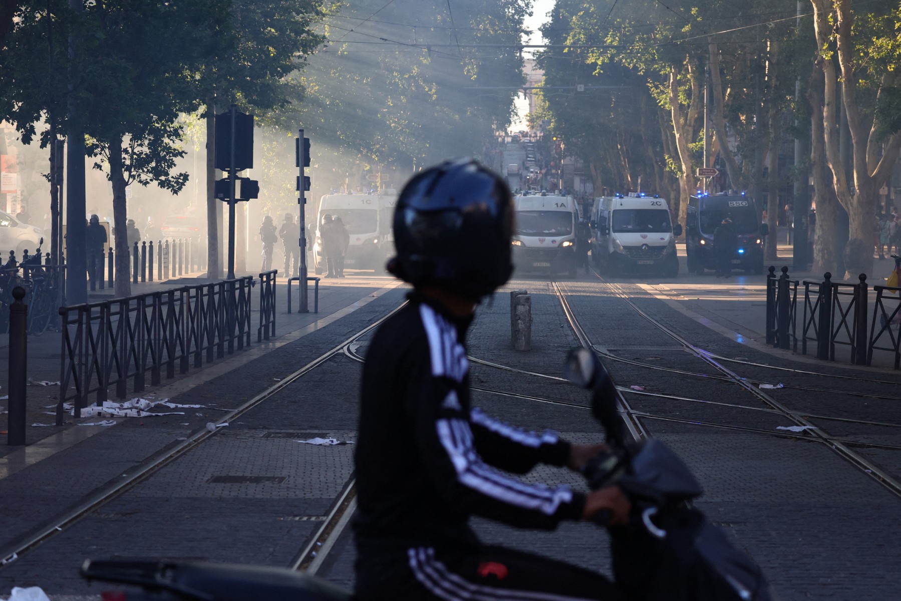 Un homme sur un scooter regarde les véhicules de la police anti-émeute française lors d'une manifestation à Marseille, dans le sud de la France, le 1er juillet 2023, après une quatrième nuit consécutive d'émeutes en France à la suite du meurtre d'un adolescent par la police. (Photo Clement Mahoudeau AFP)