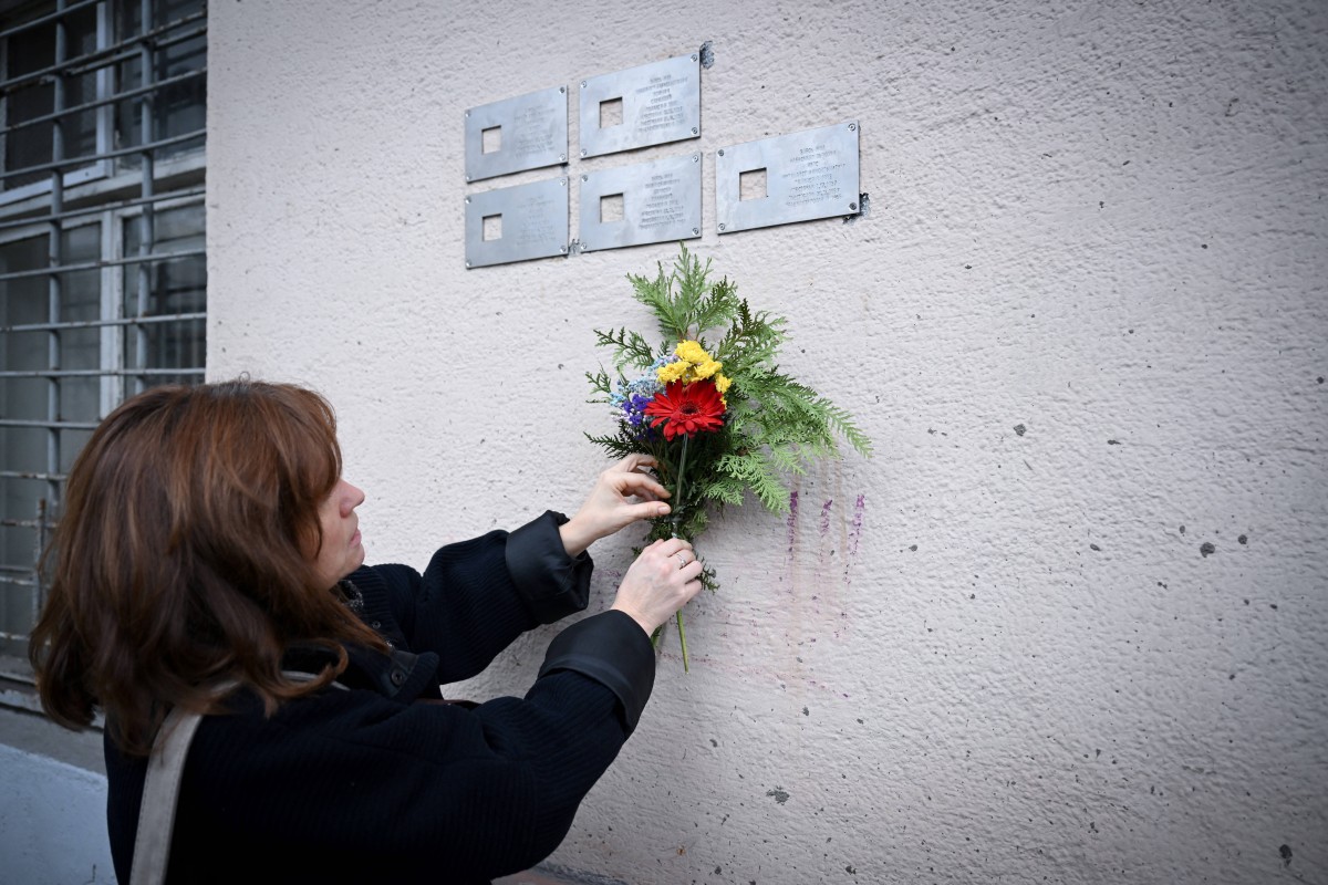 Cette photographie prise le 9 novembre 2023 montre Oksana Motievskaya, coordinatrice de la Fondation "Last Address", déposant des fleurs sous des plaques métalliques, dévoilées dans le cadre du projet appelé "Last Address" en hommage aux victimes des exécutions ordonnées par Joseph Staline à la fin des années 1930 pour marquer leur ancien domicile, fixées sur un mur d'un immeuble résidentiel à Moscou. (Photo Natalia Kolesnikova AFP)