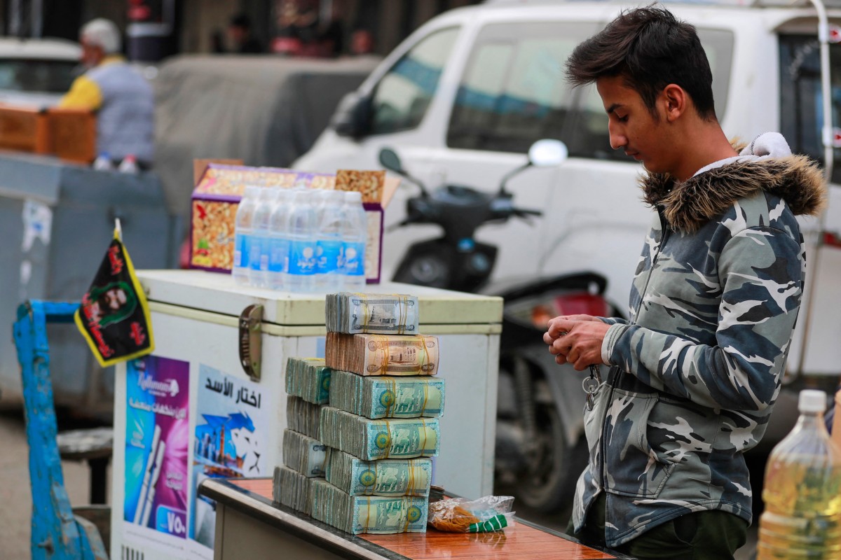 Un agent de change tient son kiosque dans la rue Al-Kifah, au centre de Bagdad, le 12 décembre 2023. (Photo Ahmad Al-Rubaye AFP)
