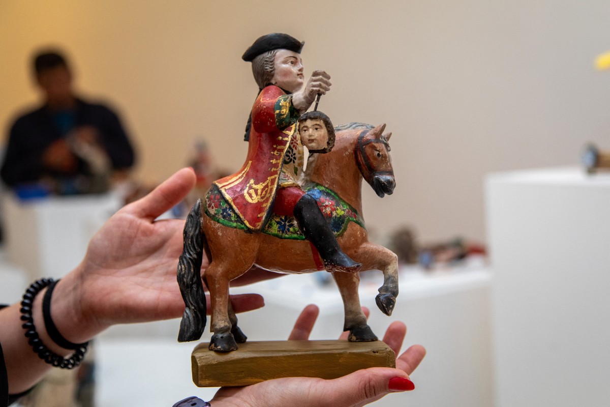 La coordinatrice du musée Del Carmen Alto, Maria Gabriela Mena, tient une figurine représentant une scène biblique et quotidienne du Quito colonial, lors du montage de la crèche au musée Del Carmen Alto de Quito, le 14 décembre 2023. Un bossu souffrant d'un goitre, un enfant décapité entre les mains d'un soldat, une femme au visage ensanglanté et d'autres images insolites composent une crèche particulière de Quito, conservée depuis trois siècles dans un monastère. (Photo Cristina Vega Rhor AFP)
