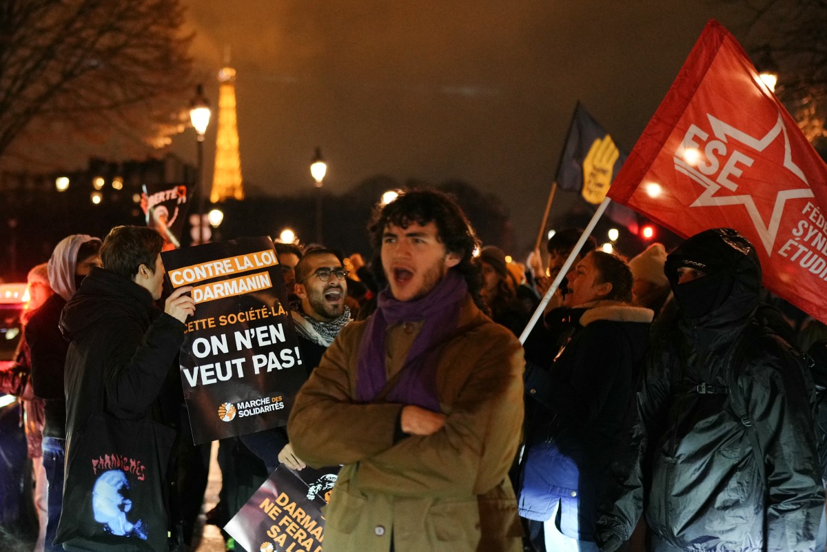 Un manifestant tient une pancarte sur laquelle on peut lire "contre la loi, nous ne voulons pas de cette société" (à gauche) lors d'une manifestation contre un projet de loi controversé sur l'immigration sur la place des Invalides à Paris le 19 décembre 2023. (Photo Dimitar Dilkoff AFP)