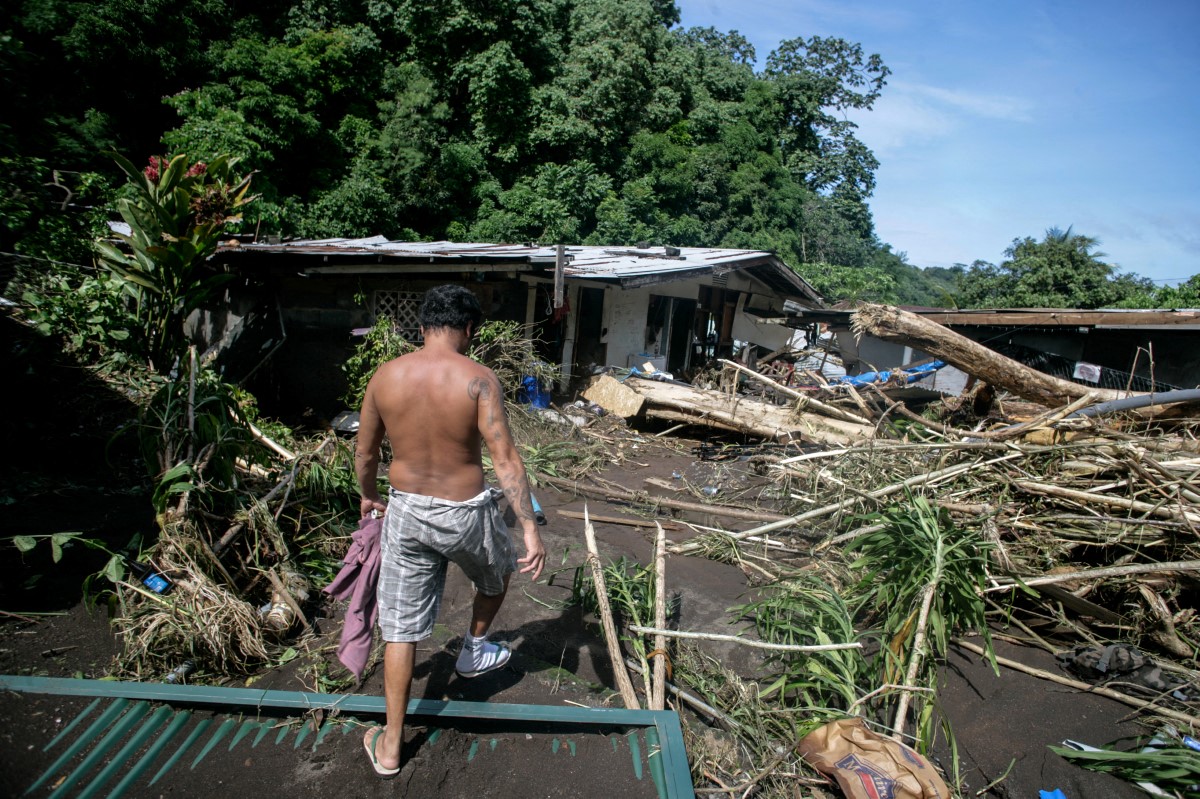 Un homme marche parmi les décombres d'un quartier endommagé dans la vallée de Nahoata, à Pirae, en périphérie de Papeete, le 23 janvier 2017 après des inondations dues à de fortes pluies, près de la ville de Punaauia, sur le territoire français d'outre-mer de Tahiti. (Photo Gregory Boissy AFP)