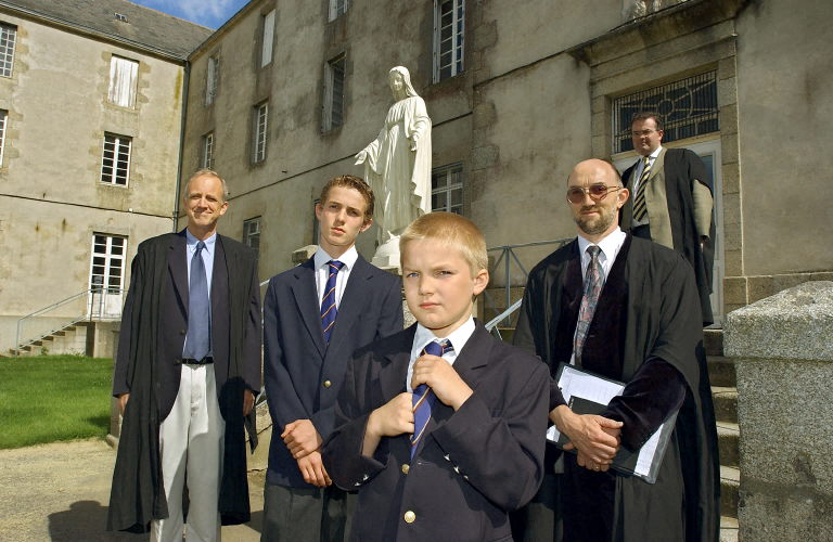 Deux élèves en uniforme scolaire posent encadrés par deux de leurs professeurs vêtus de toges de maîtres, le 24 août 2004 dans l'enceinte du Collège international catholique de Chavagnes-en-Paillers. (Photo Frank Perry AFP)