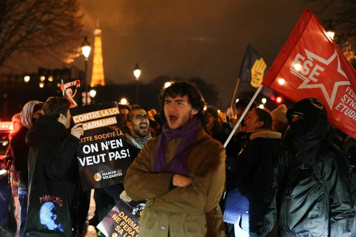 Un manifestant tient une pancarte sur laquelle on peut lire "contre la loi, nous ne voulons pas de cette société" (à gauche) lors d'une manifestation contre un projet de loi controversé sur l'immigration sur la place des Invalides à Paris le 19 décembre 2023. (Photo Dimitar Dilkoff AFP)