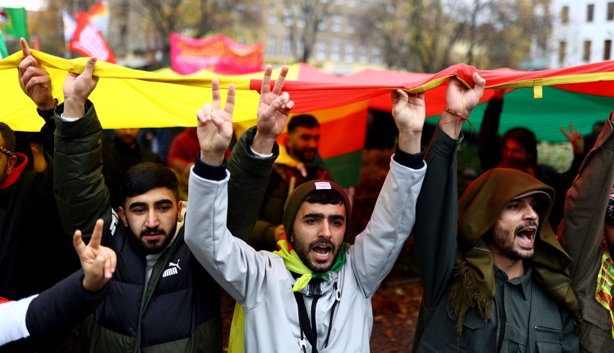 Des manifestants brandissent le drapeau tricolore de l'Administration autonome du nord et de l'est de la Syrie (AANES), également connue sous le nom de Rojava, alors qu'ils participent à une manifestation contre l'interdiction du Parti des travailleurs du Kurdistan (PKK), le 18 novembre 2023 à Berlin. (Photo par Christian Mang AFP)