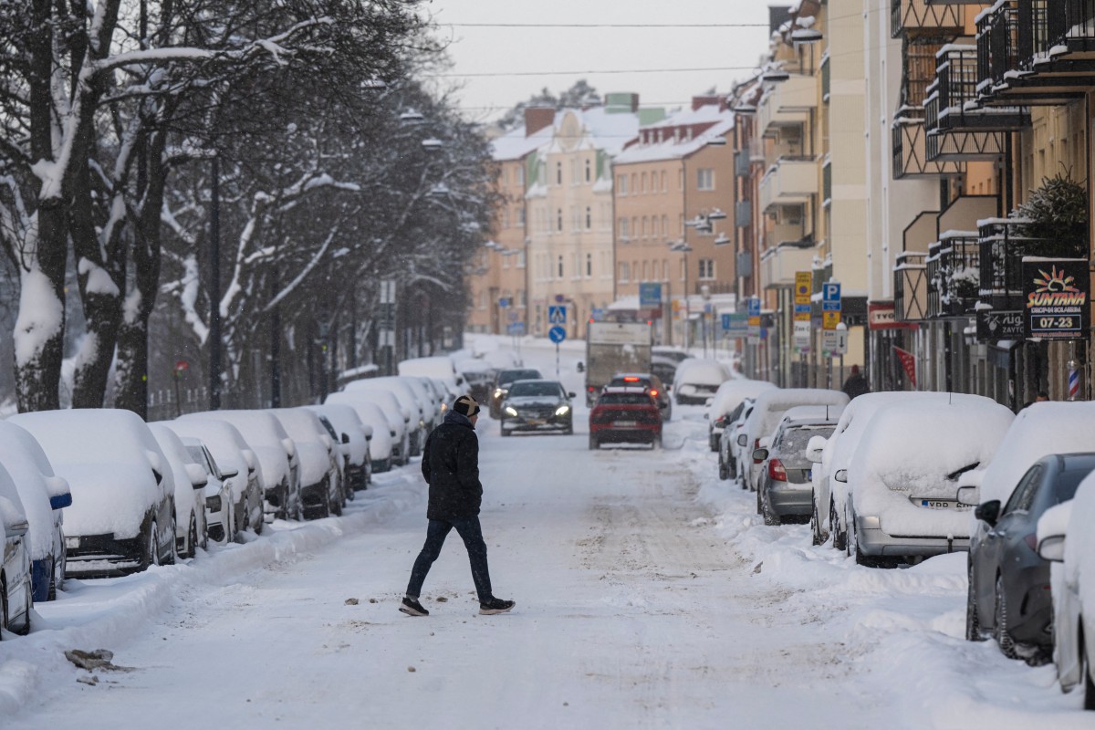 Un homme traverse une rue après une chute de neige le 4 janvier 2024 à Sundbyberg, près de Stockholm. Des températures froides allant jusqu'à -44,6°C ont été mesurées aujourd'hui près de la frontière finlandaise à la station météorologique de Karesuando, située en Laponie suédoise. (Photo Jonathan Nackstrand AFP)