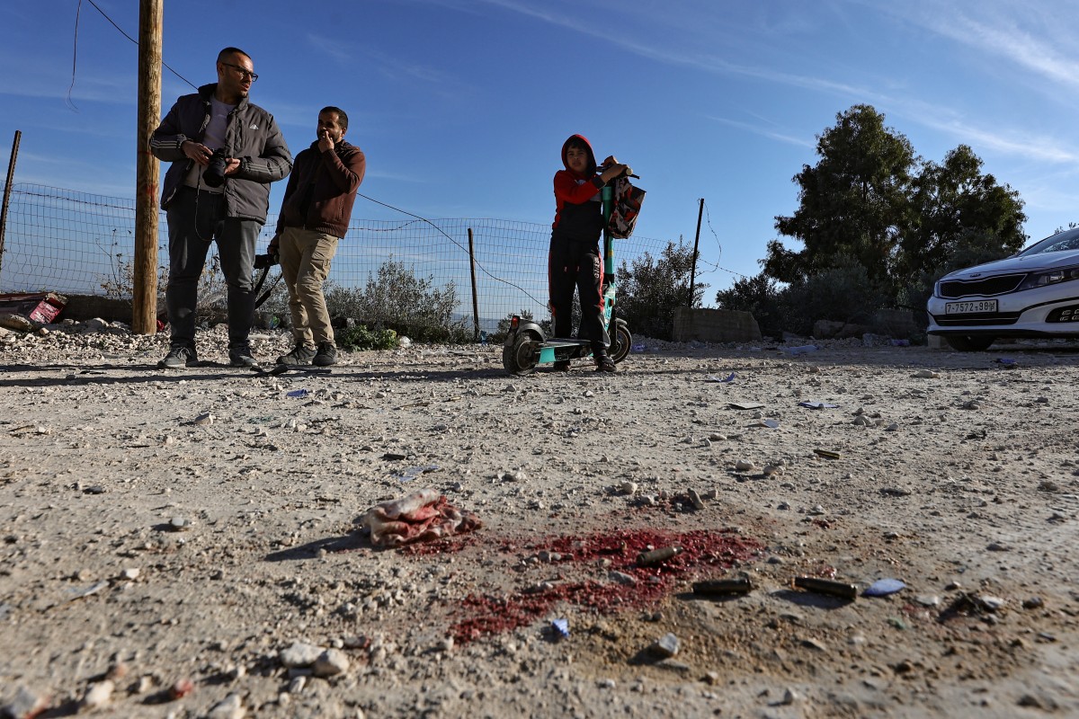 Des personnes se tiennent près de l'endroit où un engin explosif a tué un officier israélien lors d'un raid israélien à Jénine, en Cisjordanie occupée, le 7 janvier 2024. (Photo Zain Jaafar AFP)