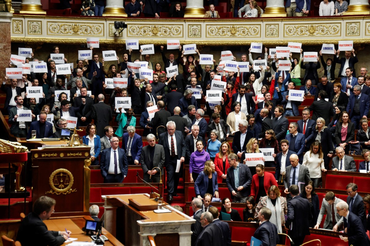 Des députés de la coalition de gauche NUPES tiennent des pancartes sur lesquelles on peut lire "Liberté", "Egalite", "Fraternité", la devise nationale de la France, après le vote et l'approbation du projet de loi visant à contrôler l'immigration, à l'Assemblée nationale française, à Paris, le 19 décembre 2023. (Photo Ludovic Marin AFP)