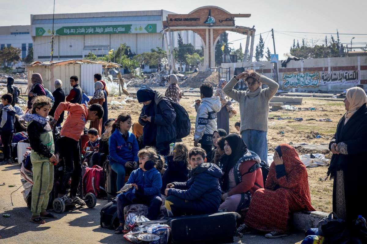 Des Palestiniens attendent devant l'université Al-Aqsa alors qu'ils fuient Khan Yunis vers des zones plus sûres plus au sud de la bande de Gaza par la sortie ouest de la ville, le 26 janvier 2024, au milieu des batailles en cours entre Israël et le groupe militant palestinien Hamas. (Photo par AFP)