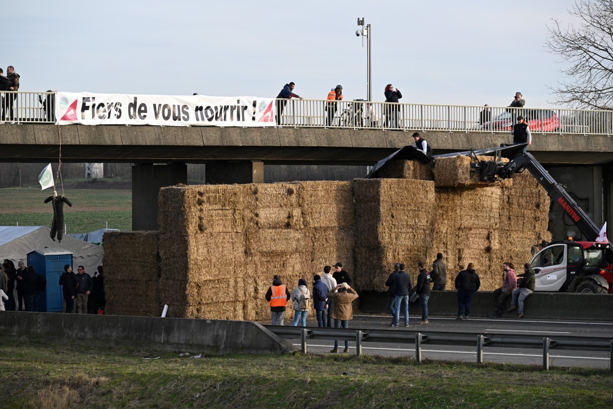 Une banderole portant l'inscription "Fiers de vous nourrir !" est visible lors d'un barrage routier tenu par des agriculteurs sur l'autoroute A4 près de Jossigny, à l'est de Paris, le 29 janvier 2024, dans le cadre de manifestations nationales organisées par plusieurs syndicats d'agriculteurs sur les salaires, les taxes et les réglementations. (Photo Bertrand Guay AFP)