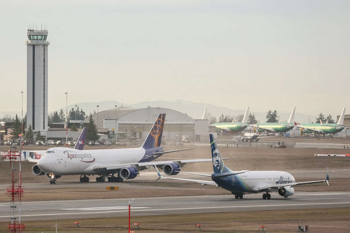 Un Boeing 737-800 d'Alaska Airlines, à droite, décolle alors que le dernier 747 produit par Boeing, un 747-8 Freighter pour Atlas Air, roule avant de décoller de Paine Field à Everett, Washington, le 1er février 2023. (Photo Jason Redmond AFP)
