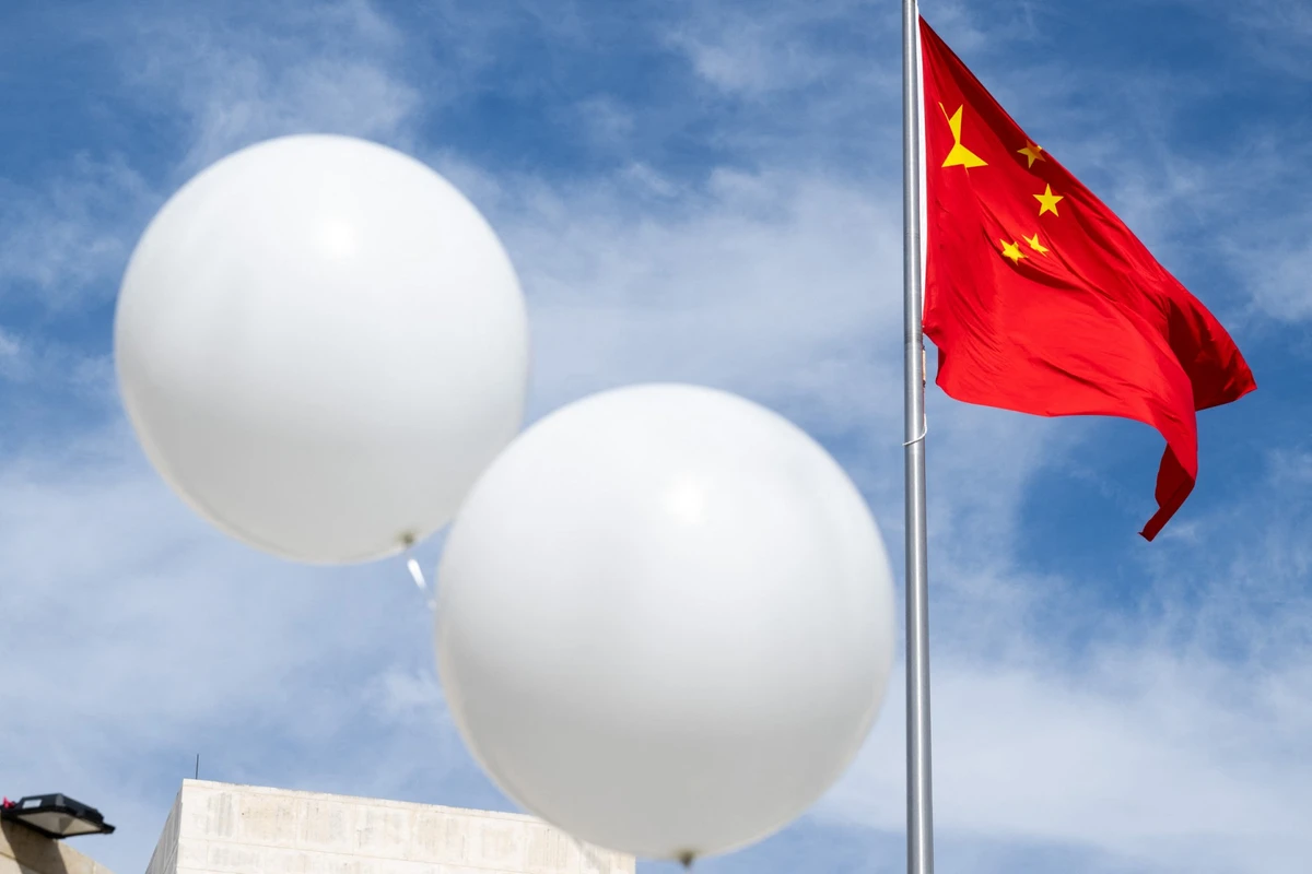 Deux ballons blancs flottent près du drapeau chinois alors que le révérend Patrick Mahoney proteste contre le gouvernement chinois au sujet du ballon de surveillance chinois qui aurait été abattu au-dessus des États-Unis la semaine dernière, lors d'une manifestation devant l'ambassade de Chine à Washington, DC, le 15 février 2023. (Photo par Saul Loeb AFP)