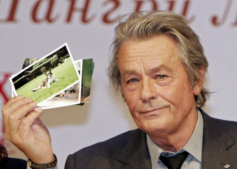 L'acteur français Alain Delon montre des photos de deux chiens qui lui ont été offerts par Alexander Lebed, un général et homme politique russe décédé en avril 2002 dans un accident d'hélicoptère en Sibérie, lors de sa conférence de presse à Moscou, le 16 mars 2005. Alain Delon est arrivé à Moscou pour participer au Festival international du film "Faces of Love". (Photo Frank Viliagra, GAZETA, AFP)