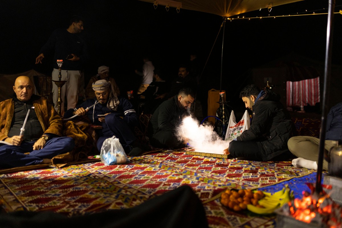 Des campeurs irakiens jouent au backgammon tandis que d'autres fument une pipe à eau à l'intérieur de leur tente dans le désert de Samawa, au sud de Bagdad, le 2 février 2024. Loin de l'agitation des grandes villes, les jeunes Irakiens profitent de plus en plus d'un sentiment de sécurité renouvelé pour explorer les escapades sereines du pays dans le désert. (Photo Hussein Faleh AFP)