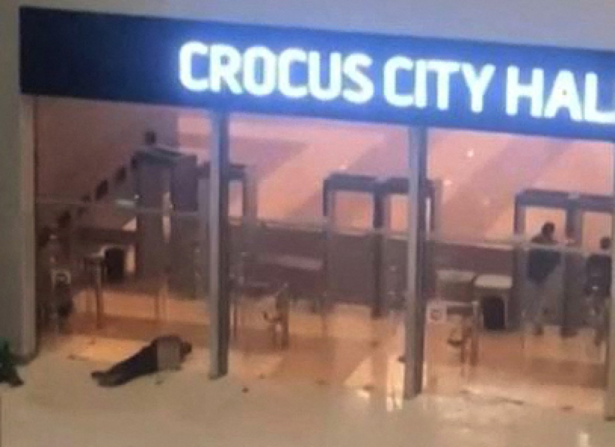 Cette image tirée d'une séquence obtenue par AFP TV montre des hommes armés non identifiés (à droite) franchissant les portes du Crocus City Hall à Krasnogorsk, dans la banlieue de Moscou, le 22 mars 2024. (Photo UGC AFP)