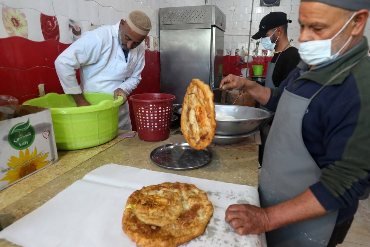 Un employé emballe du sfinz fraîchement frit, un pain frit spongieux qui peut être servi nature ou avec des œufs, à Tripoli le 14 mars 2024 pendant le ramadan (Photo, AFP).