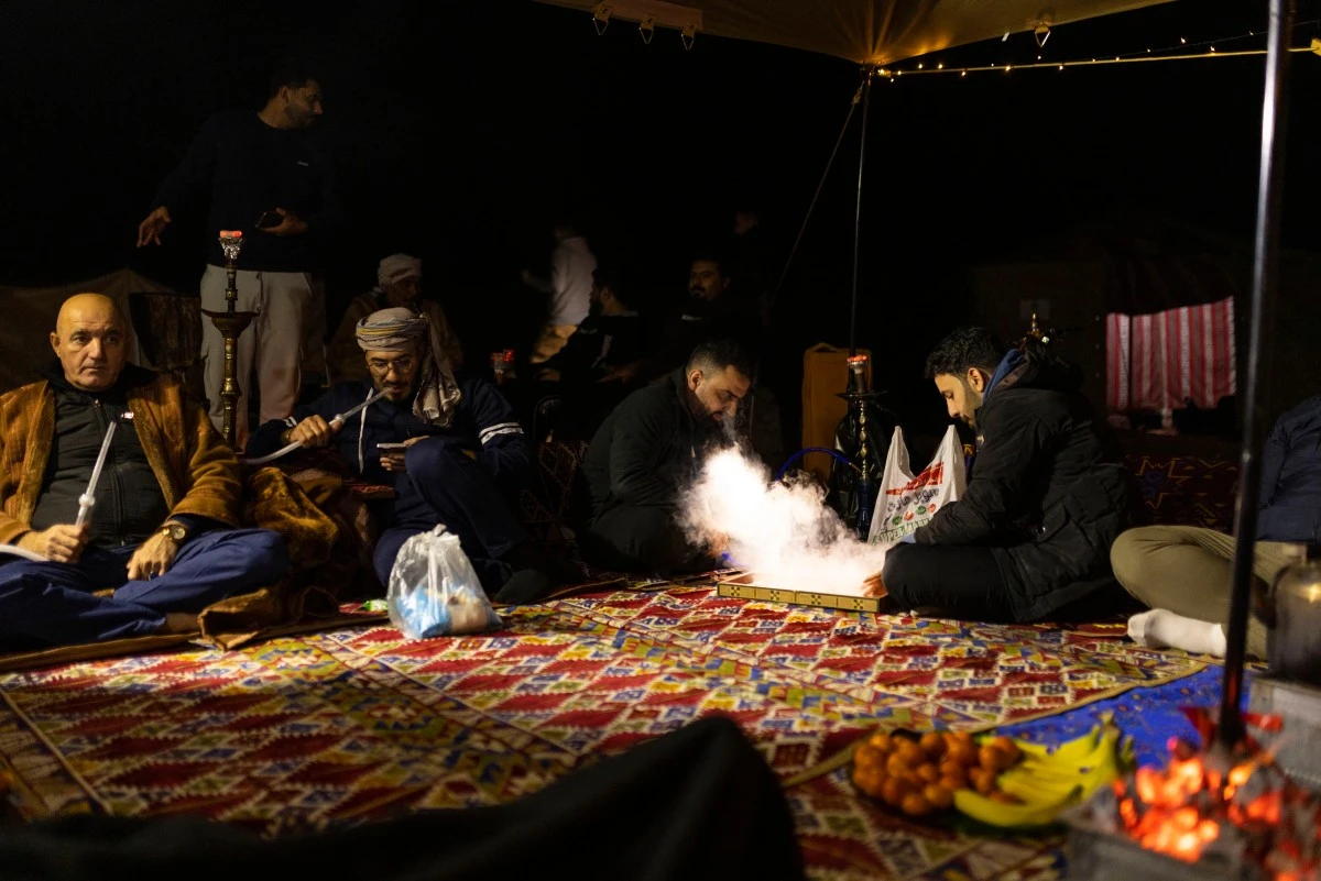 Des campeurs irakiens jouent au backgammon tandis que d'autres fument une pipe à eau à l'intérieur de leur tente dans le désert de Samawa, au sud de Bagdad, le 2 février 2024. Loin de l'agitation des grandes villes, les jeunes Irakiens profitent de plus en plus d'un sentiment de sécurité renouvelé pour explorer les escapades sereines du pays dans le désert. (Photo Hussein Faleh AFP)