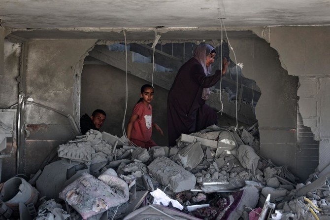 Une femme et des enfants palestiniens vérifient les décombres d'un bâtiment touché par un bombardement israélien à Rafah, dans le sud de la bande de Gaza, le 20 avril 2024. (AFP)
