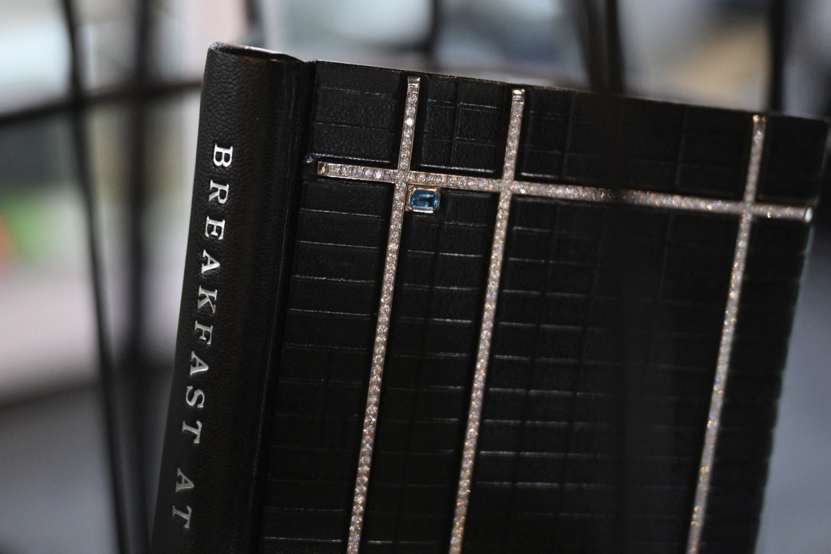 Une reliure personnalisée d'une première édition signée de "Breakfast at Tiffany's" par Truman Capote est présentée à la Foire internationale du livre ancien de New York (ABAA) le 4 avril 2024. Le modèle comporte plus de 1 000 diamants blancs, une aigue-marine d'un carat de taille émeraude et est estimé à environ 1 500 000 dollars. (Photo par Angela WEISS AFP)
