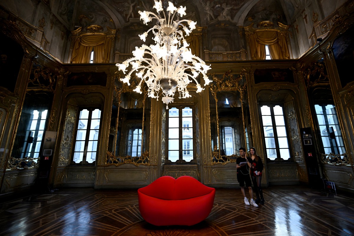 Des visiteurs regardent le canapé "La Bocca" (La Bouche) présenté par Gufram, au Palazzo Litta dans le cadre de l'événement Fuorisalone 2024, à la veille de la Semaine du design de Milan, à Milan, le 15 avril 2024. (Photo Gabriel Bouys AFP)