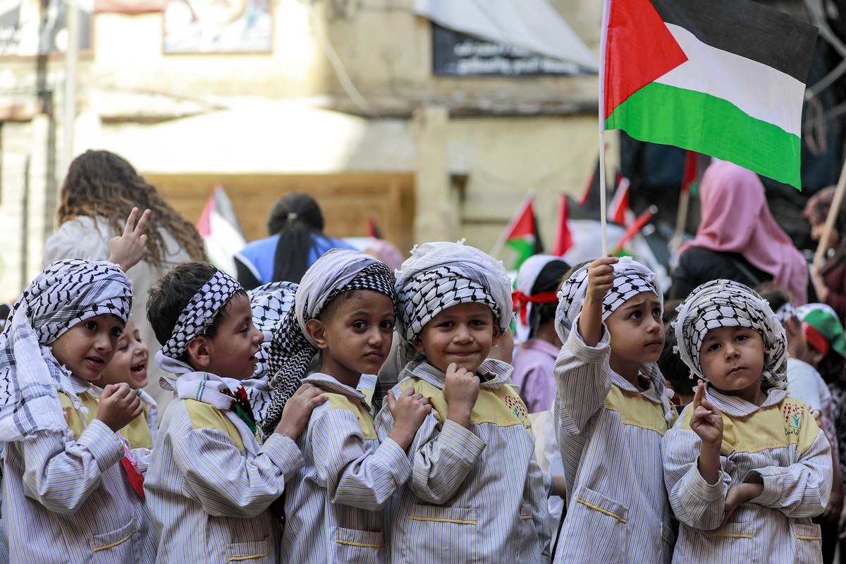 Un écolier tient un drapeau palestinien alors qu’il se tient avec d’autres personnes portant des foulards keffiyeh palestiniens lors d’une manifestation de sit-in au camp de réfugiés palestiniens de Shatila dans la banlieue sud de Beyrouth le 7 novembre 2023. (AFP)