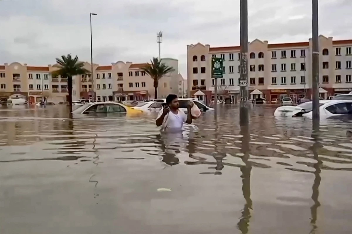 Dans cette capture vidéo de l'AFPTV, un homme patauge dans une rue inondée à Dubaï le 16 avril 2024. Dubaï, le centre financier du Moyen-Orient, a été paralysé par les pluies torrentielles qui ont provoqué des inondations dans les Émirats arabes unis et à Bahreïn et qui ont fait 18 morts à Oman les 14 et 15 avril (Photo Atif Bhatti / ESN / AFP).