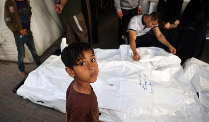 Un jeune garçon regarde les parents des Palestiniens tués dans un bombardement israélien, pleurer près de leurs corps dans la cour de l'hôpital al-Najjar à Rafah dans le sud de la bande de Gaza le 3 mai 2024, dans le cadre du conflit en cours entre Israël et le mouvement Hamas. (AFP)