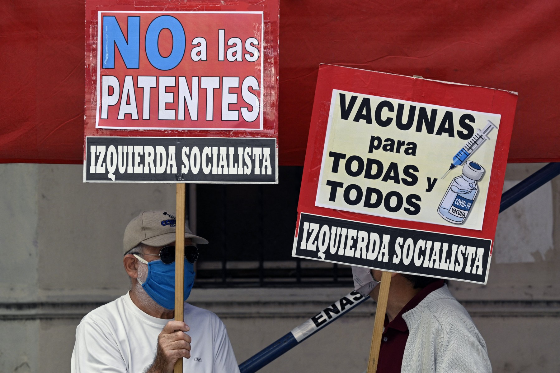 Des personnes brandissent des banderoles sur lesquelles on peut lire "Des vaccins pour tous" et "Non aux brevets" lors d'une manifestation de membres de partis de gauche devant le siège de l'Organisation mondiale de la santé (OMS) à Buenos Aires, le 14 avril 2021, dans le contexte de la pandémie de coronavirus. (photo Juan Mabromata, AFP)