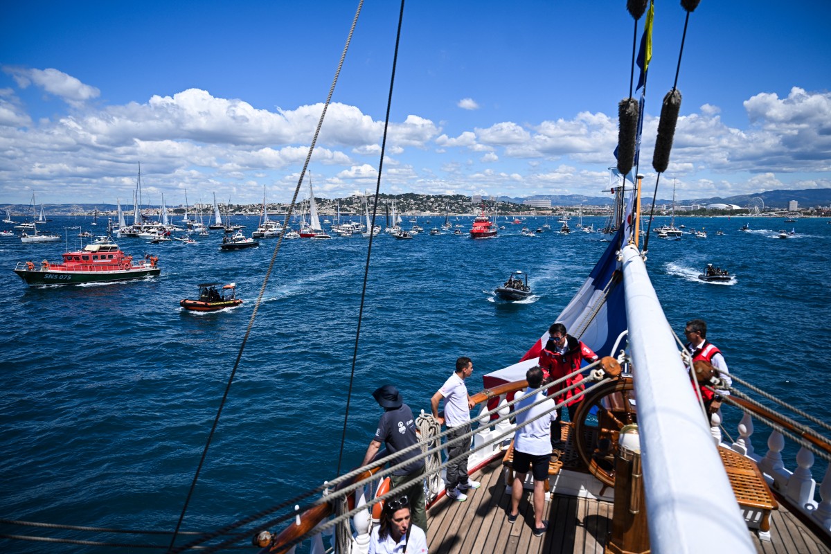 Cette photographie montre le trois-mâts français Belem, datant du XIXe siècle, escorté par les plaisanciers alors qu'il navigue près de la côte de Marseille, le 8 mai 2024, avant d'accoster avec la torche olympique, en vue des Jeux olympiques et paralympiques de Paris 2024. (Photo Nicolas Tucat / AFP)