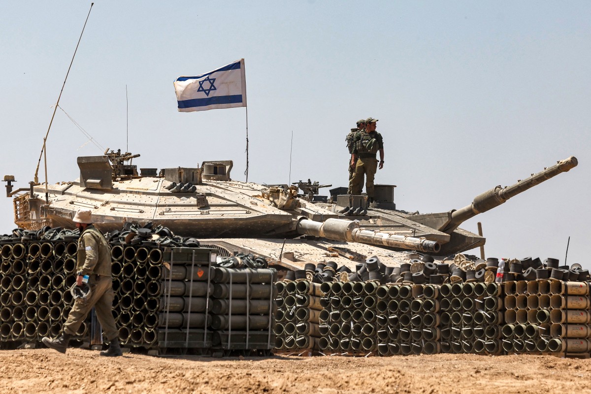 Des soldats de l'armée israélienne se tiennent debout sur la tourelle d'un char de combat principal positionné dans le sud d'Israël près de la frontière avec la bande de Gaza, le 9 mai 2024. (Photo par Ahmad Gharabli AFP)