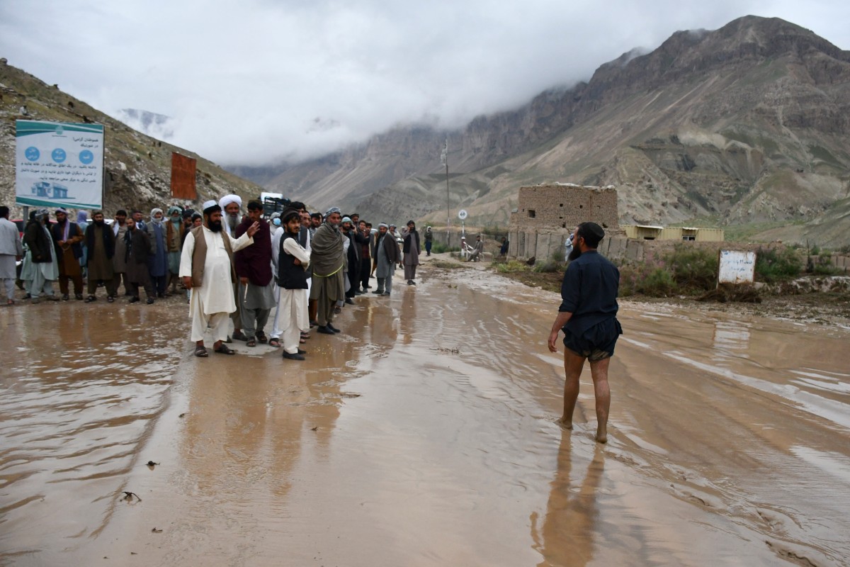 Des Afghans se rassemblent le long d'une route entre Samangan et Mazar-i-Sharif couverte de boue à la suite d'une crue soudaine après de fortes pluies, dans le district de Feroz Nakhchir de la province de Samangan, le 11 mai 2024. (Photo par Atif Aryan AFP)