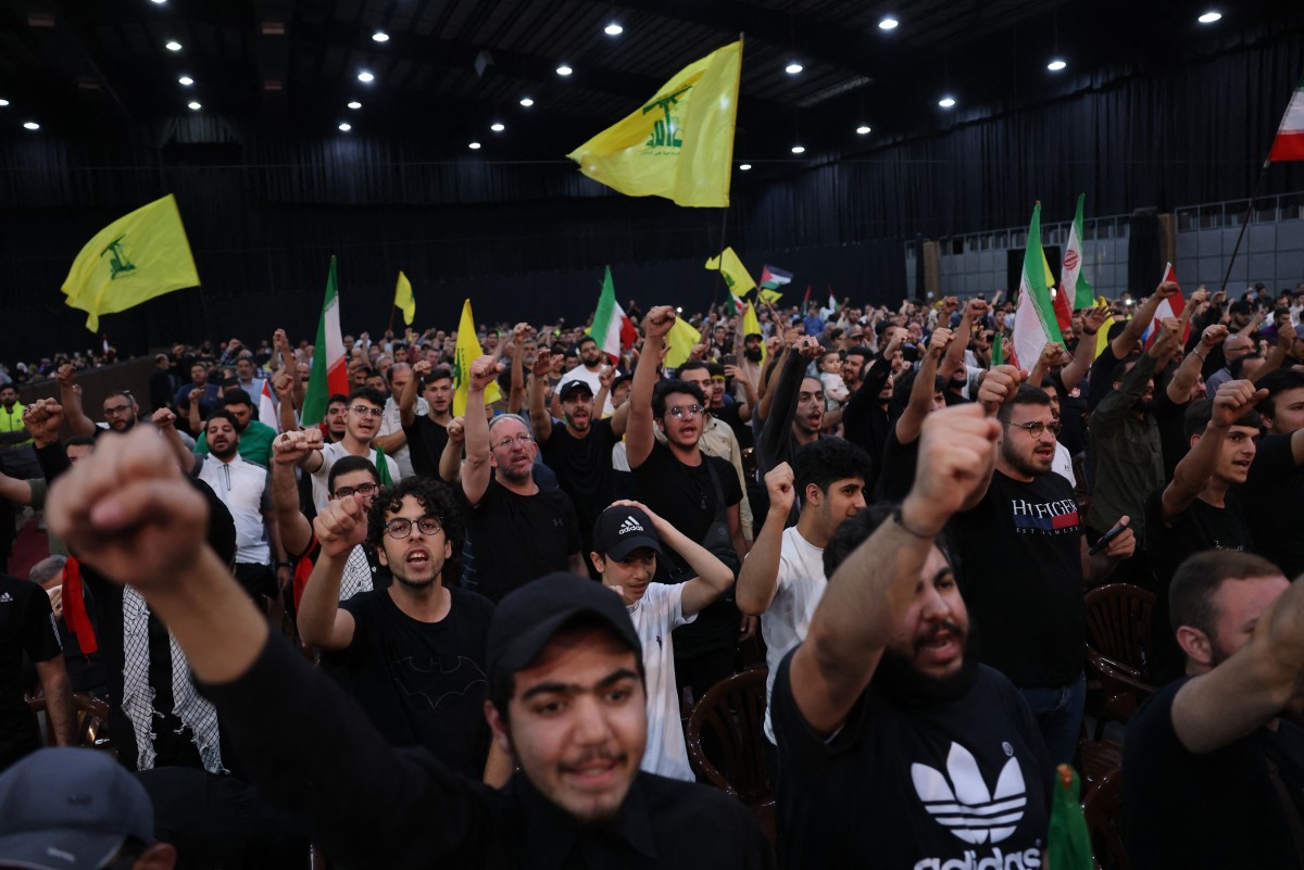 Des personnes brandissent des drapeaux iraniens et du Hezbollah lors d'un rassemblement pour pleurer la mort du président iranien Ebrahim Raisi et de son entourage, tués dans un récent accident d'hélicoptère, dans la banlieue sud de Beyrouth, le 24 mai 2024. (Photo Anwar Amro / AFP)