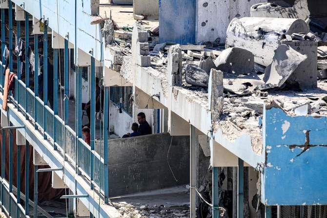 Un homme et des enfants sont photographiés sur le balcon d'une école gérée par l'UNRWA qui a été touchée par les bombardements israéliens, dans le camp de Nuseirat dans le centre de la bande de Gaza, le 7 juin 2024. (AFP)