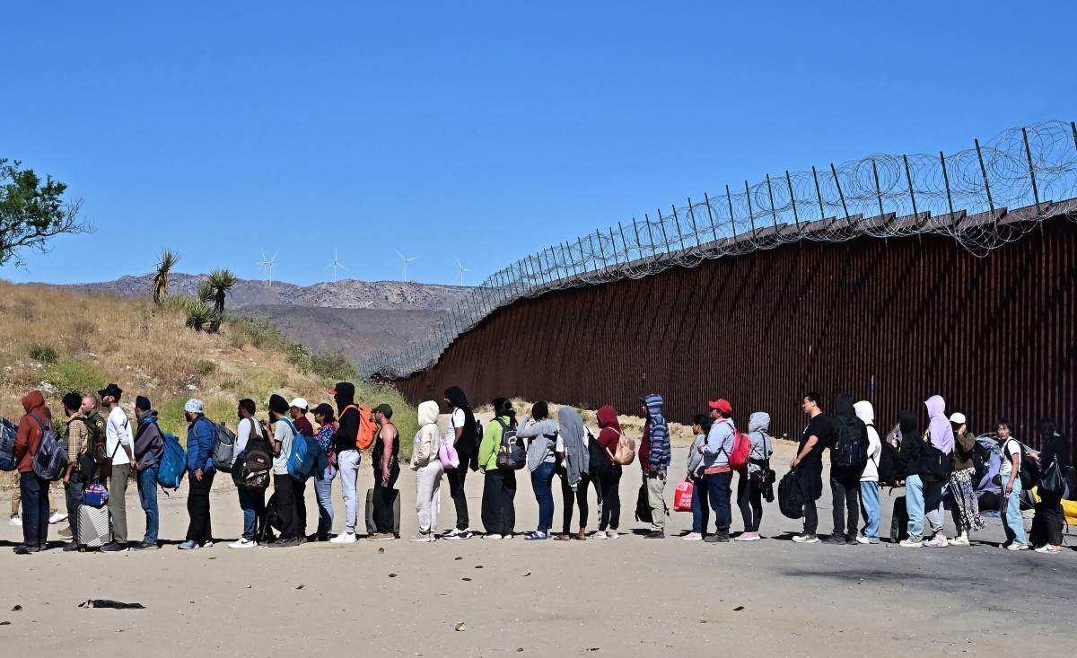 Des migrants font la queue dans l'espoir d'être pris en charge par les agents des douanes et de la patrouille frontalière après que des groupes soient arrivés à Jacumba Hot Springs, en Californie, après avoir marché sous une chaleur intense depuis le Mexique jusqu'aux États-Unis, le 5 juin 2024. (Photo Frederic J. Brown AFP)