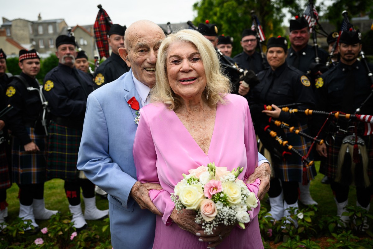 Jeanne Swerlin, 96 ans, (à droite) et Harold Terens, 100 ans, vétéran américain de la Seconde Guerre mondiale, (à gauche) posent pour des photos devant un groupe de joueurs de cornemuse alors qu'ils célèbrent leur mariage à la mairie de Carentan-les-Marais, en Normandie, dans le nord-ouest de la France, le 8 juin 2024, quelques jours après avoir été honorés à l'occasion du 80e anniversaire du Débarquement qui a eu lieu à quelques kilomètres de là. (Photo Loic Venance / AFP)