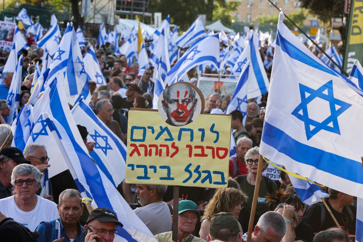 Des personnes brandissent des drapeaux et des pancartes lors d'un rassemblement anti-gouvernemental devant le Parlement israélien à Jérusalem, appelant à des élections anticipées le 17 juin 2024, dans le cadre du conflit actuel dans la bande de Gaza entre Israël et le mouvement militant palestinien Hamas. (Photo de Menahem Kahana AFP)