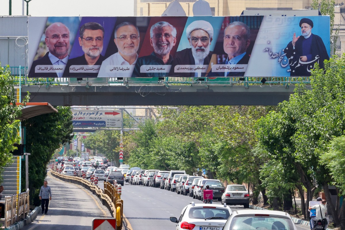 Des véhicules passent devant un panneau d'affichage montrant les visages des six candidats à la présidence (de gauche à droite) : Mohammad Bagher Ghalibaf, Amirhossein Ghazizadeh-Hashemi, Alireza Zakani, Saeed Jalili, Mostafa Pourmohammadi et Masoud Pezeshkianin, à Téhéran, capitale de l'Iran, le 29 juin 2024. (Photo par Atta Kenare AFP)
