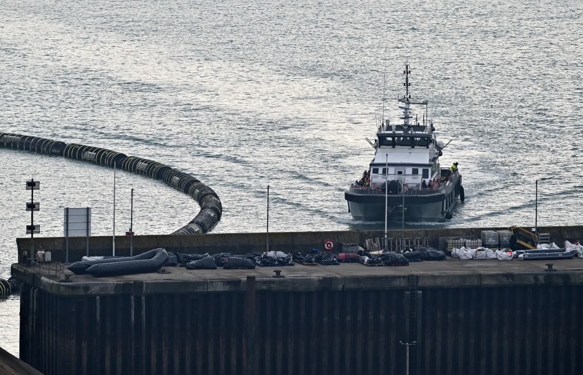 Le navire des forces frontalières « BF Volunteer » transportant des migrants ramassés en mer et tentant de traverser la Manche depuis la France, passe devant des canots pneumatiques utilisés par les migrants lors de précédentes tentatives de traversée, stockés sur le quai, alors qu'il arrive à la marina de Douvres, dans le sud-est de l'Angleterre, le 7 septembre 2024. (AFP)