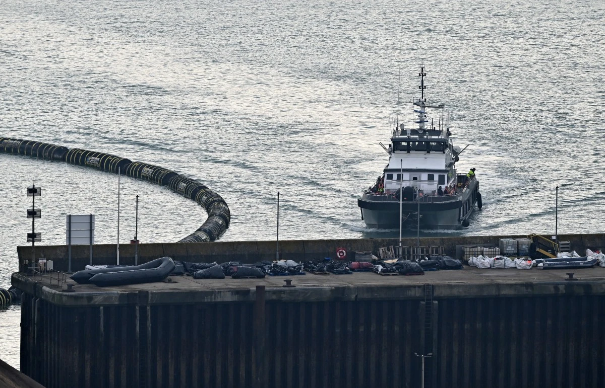 Le navire des forces frontalières « BF Volunteer » transportant des migrants ramassés en mer et tentant de traverser la Manche depuis la France, passe devant des canots pneumatiques utilisés par les migrants lors de précédentes tentatives de traversée, stockés sur le quai, alors qu'il arrive à la marina de Douvres, dans le sud-est de l'Angleterre, le 7 septembre 2024. (AFP)