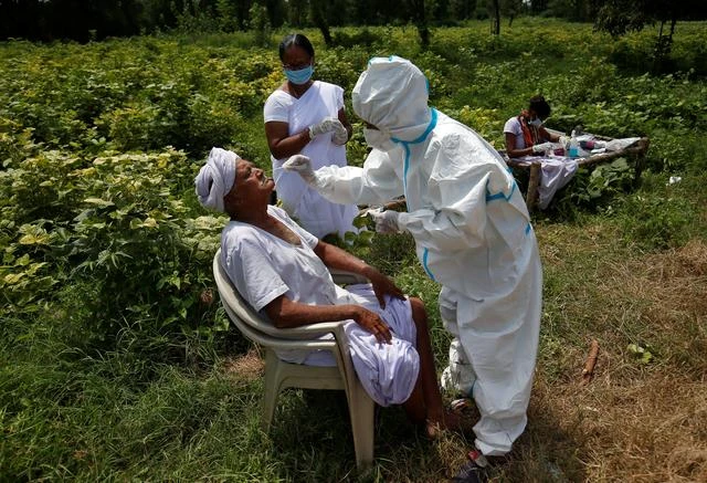 A healthcare worker takes a swab from a farmer in a field amid the COVID-19 outbreak, Kavitha, Gujarat, India, Sept. 15, 2020. (Reuters)