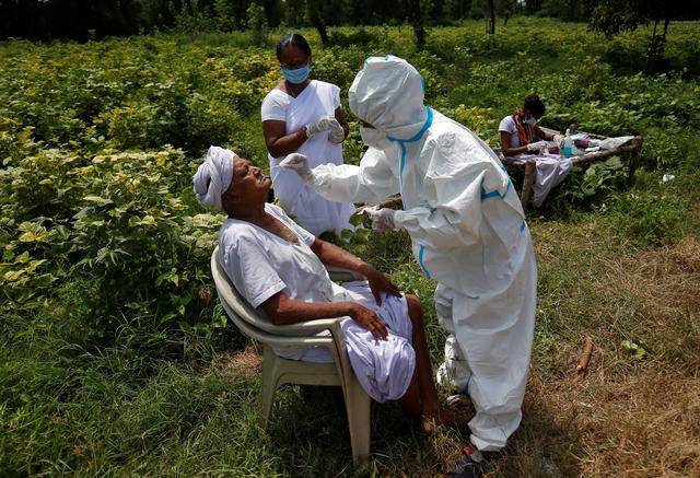 A healthcare worker takes a swab from a farmer in a field amid the COVID-19 outbreak, Kavitha, Gujarat, India, Sept. 15, 2020. (Reuters)