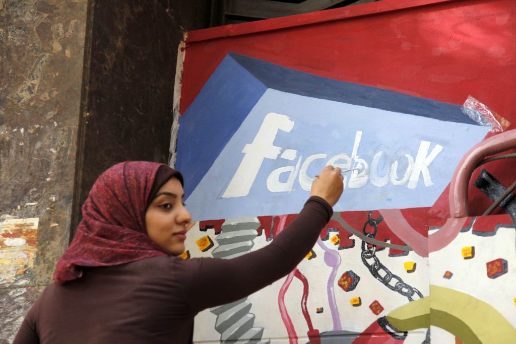 An art student from the University of Helwan paints the Facebook logo on a mural in the Zamalek neighborhood of Cairo, Egypt, Mar. 30, 2011. (AP Photo)