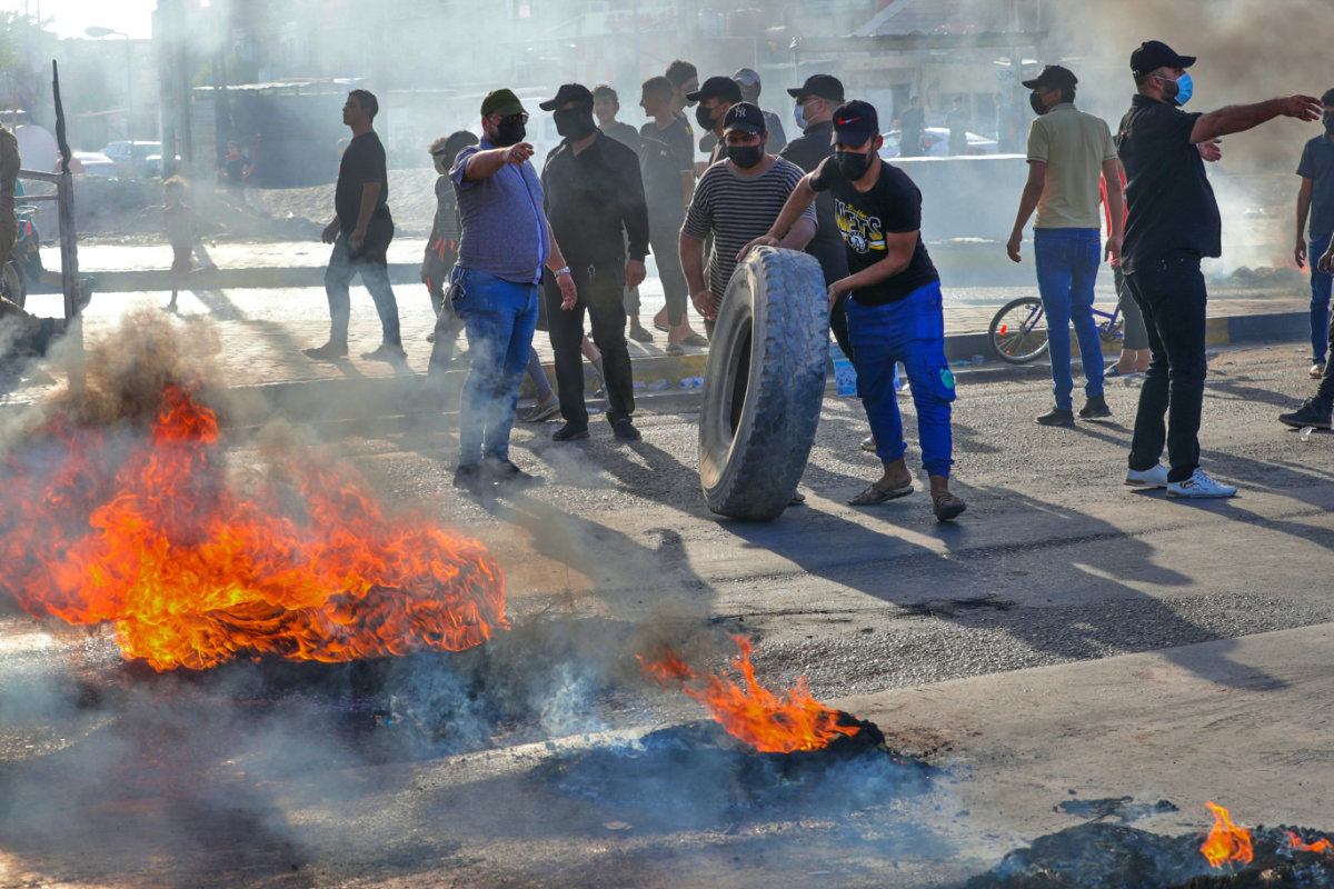 Supporters of hardline Iraqi Shiite factions block streets and burn tires in Basra, Iraq, after the Electoral Commission announced the results of the parliamentary elections on Oct. 17, 2021. (AP Photo/Nabil al-Jurani)